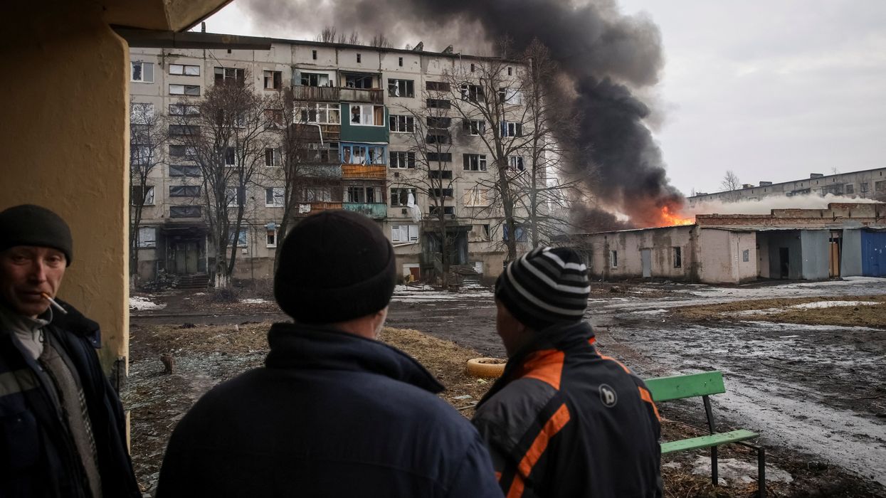 Three men watching an explosion in Ukraine