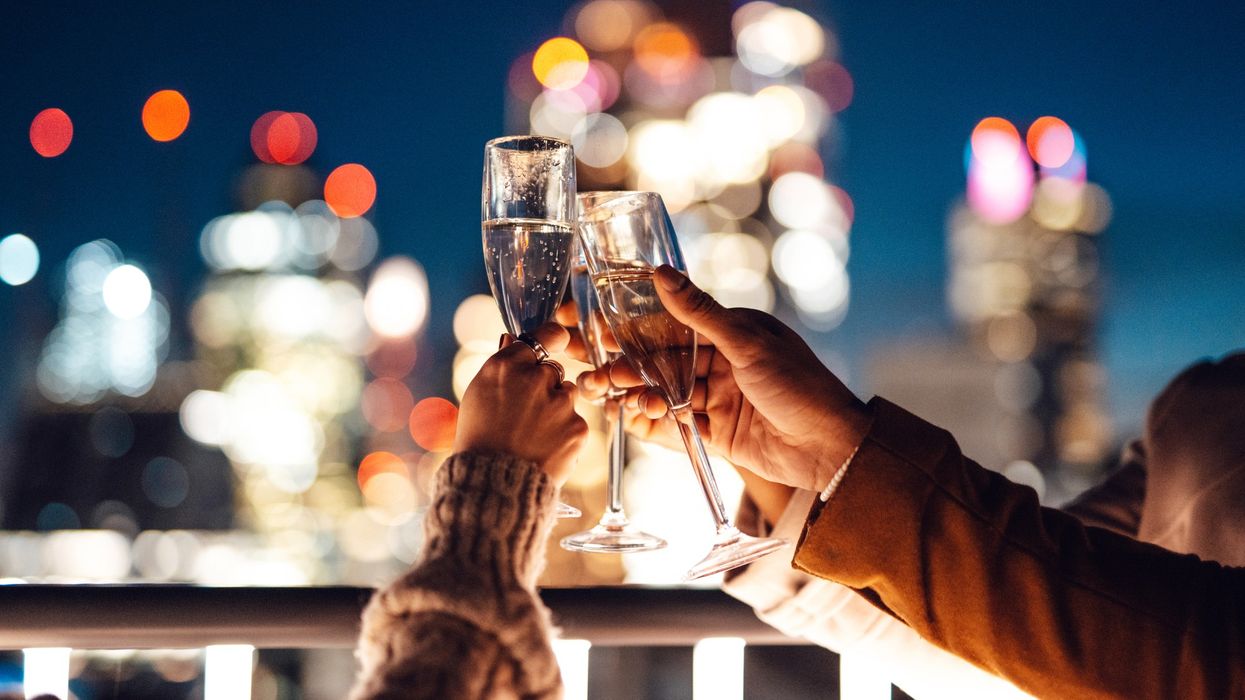 three people clink glasses of sparkling wine together on a rooftop bar