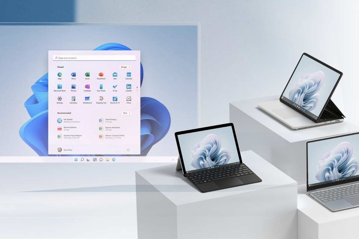 three surface PCs are pictured on the right-side with a screenshot from Windows 11 in the background 
