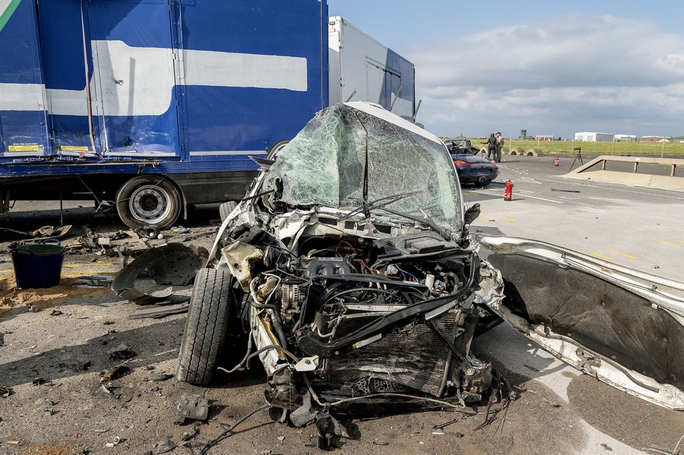 Totally unrecognisable Caravan Dodge with severe damage lies next to the lorry post-crash