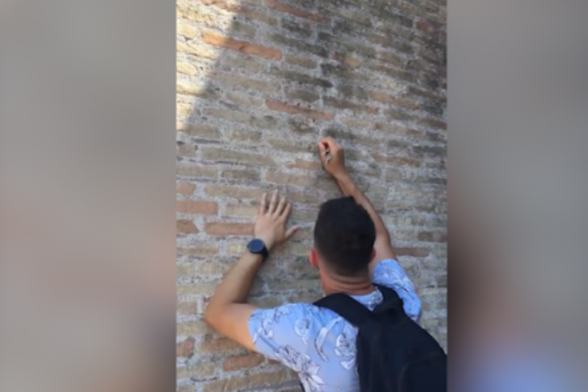 Tourist defacing walls of Rome Colloseum