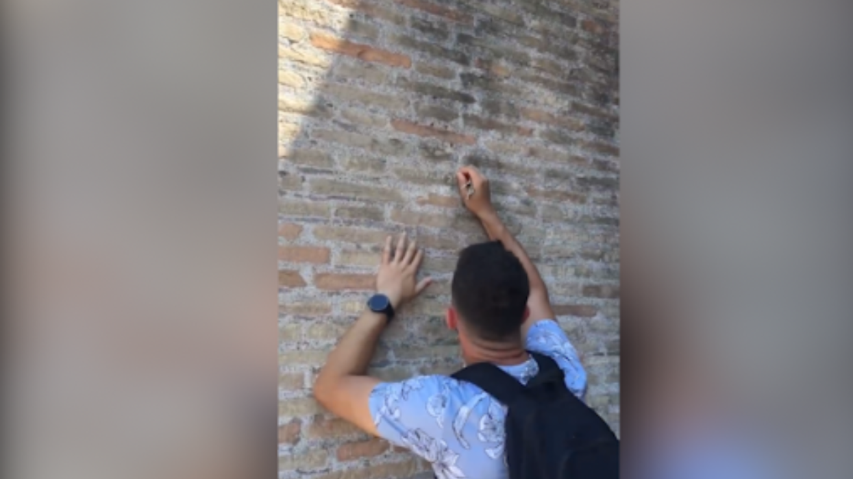 Tourist defacing walls of Rome Colloseum