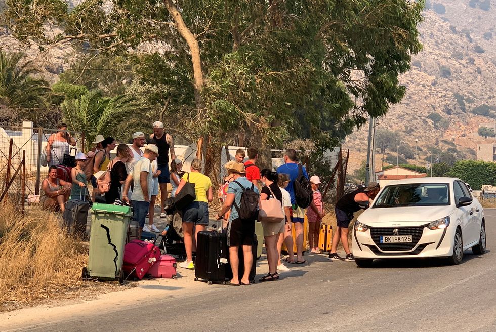 Tourists sat on the roadside after being evacuated