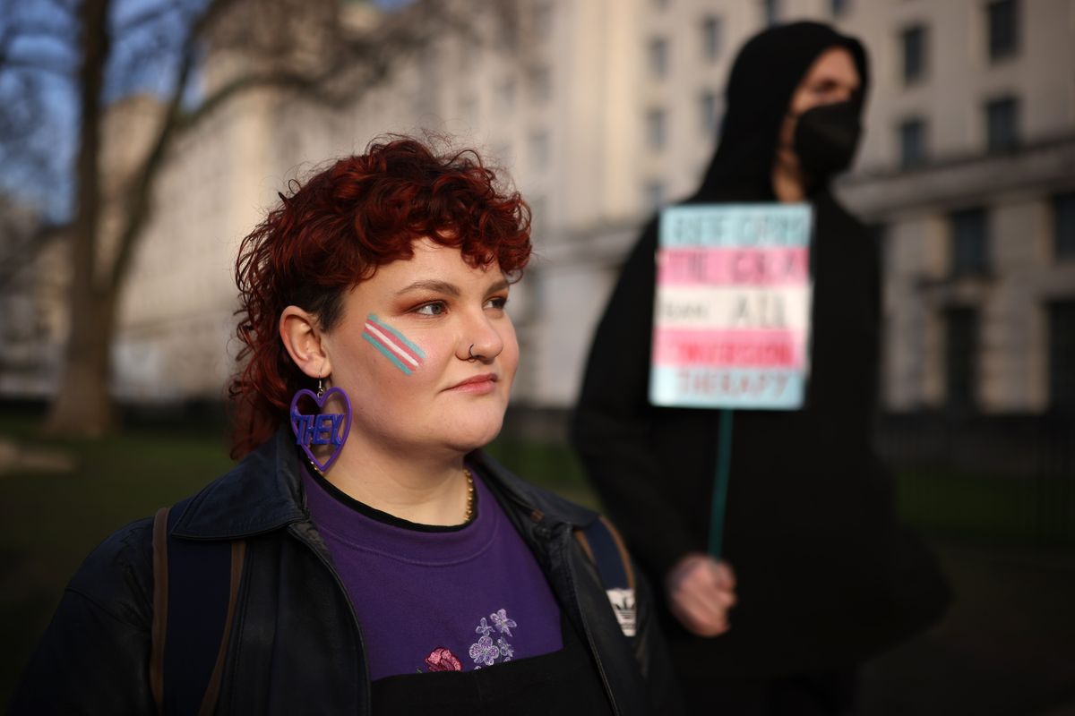 Trans rights activist wears an earring featuring a 'they' pronoun symbol, during a protest outside the Ministry of Defence Main Building