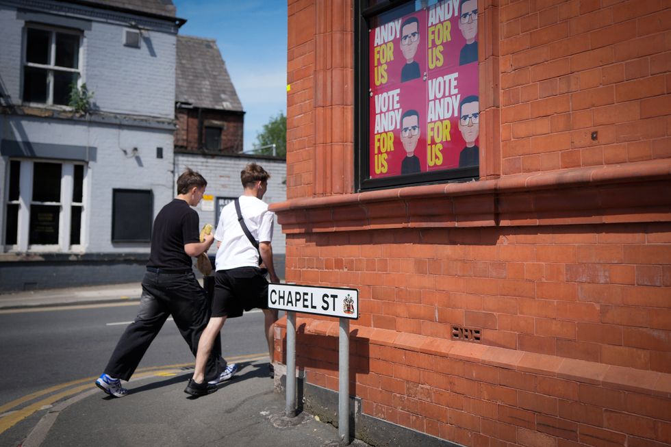 Two boys walking around from Andy Burnham posters