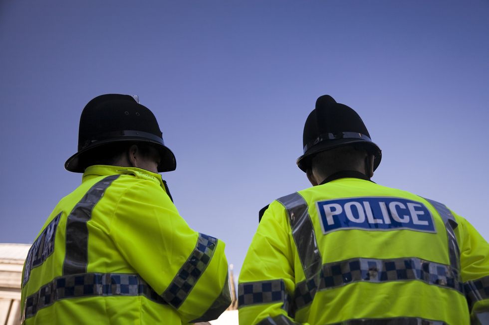 Two British Policemen wearing Traditional Helmets