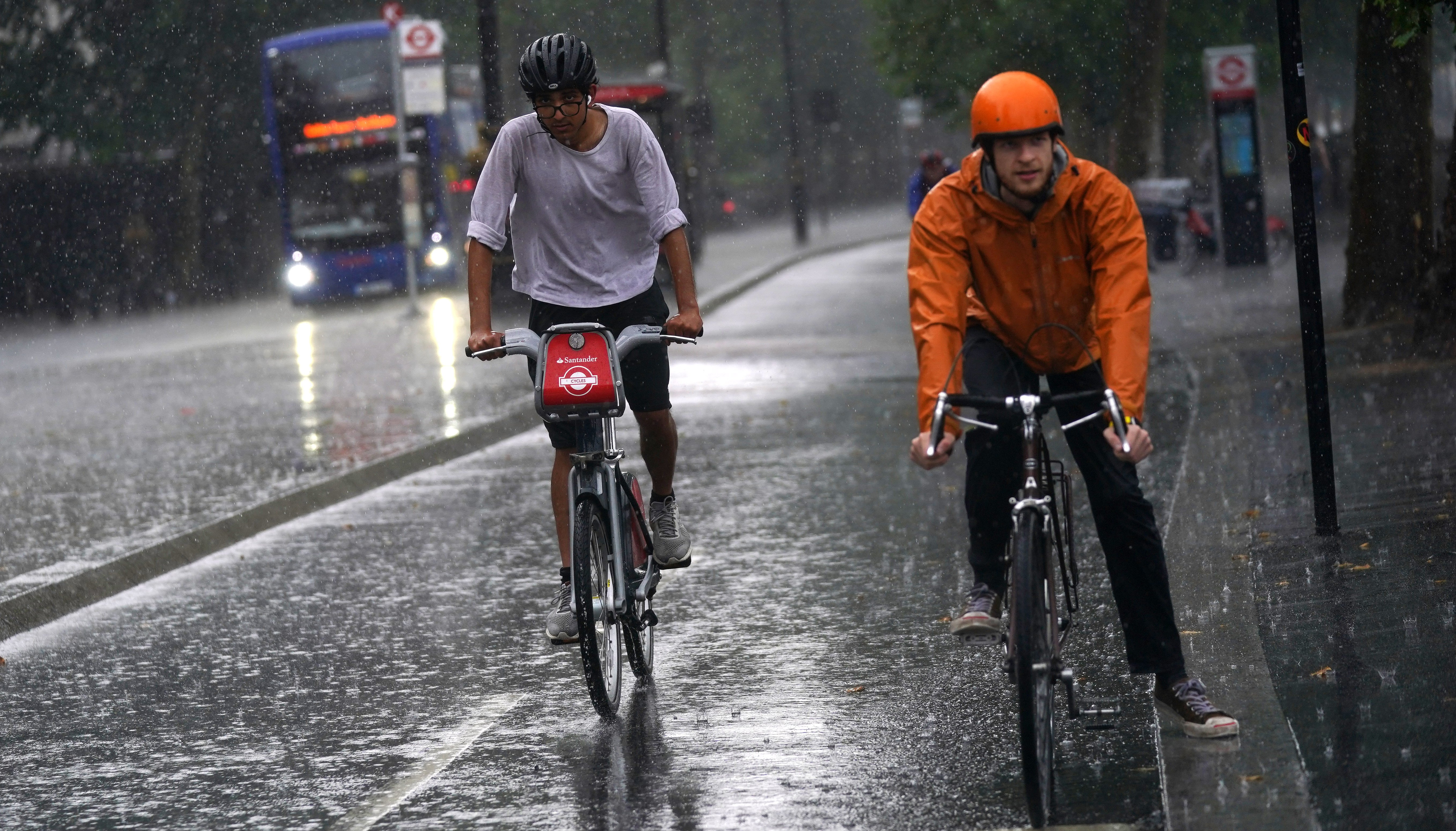Two cyclists ride along the Embankment as heavy rain sweeps through central London.