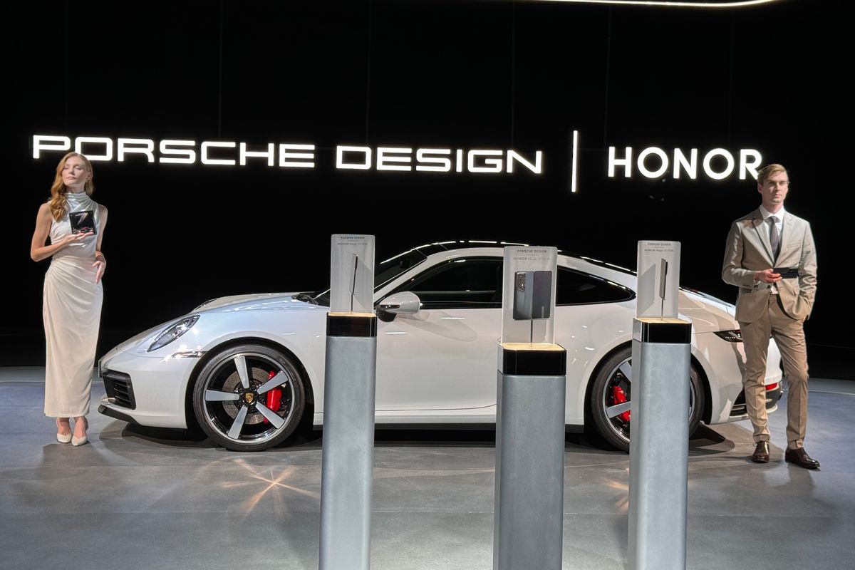 two models hold the Porsche design Honor smartphone with a supercar behind them