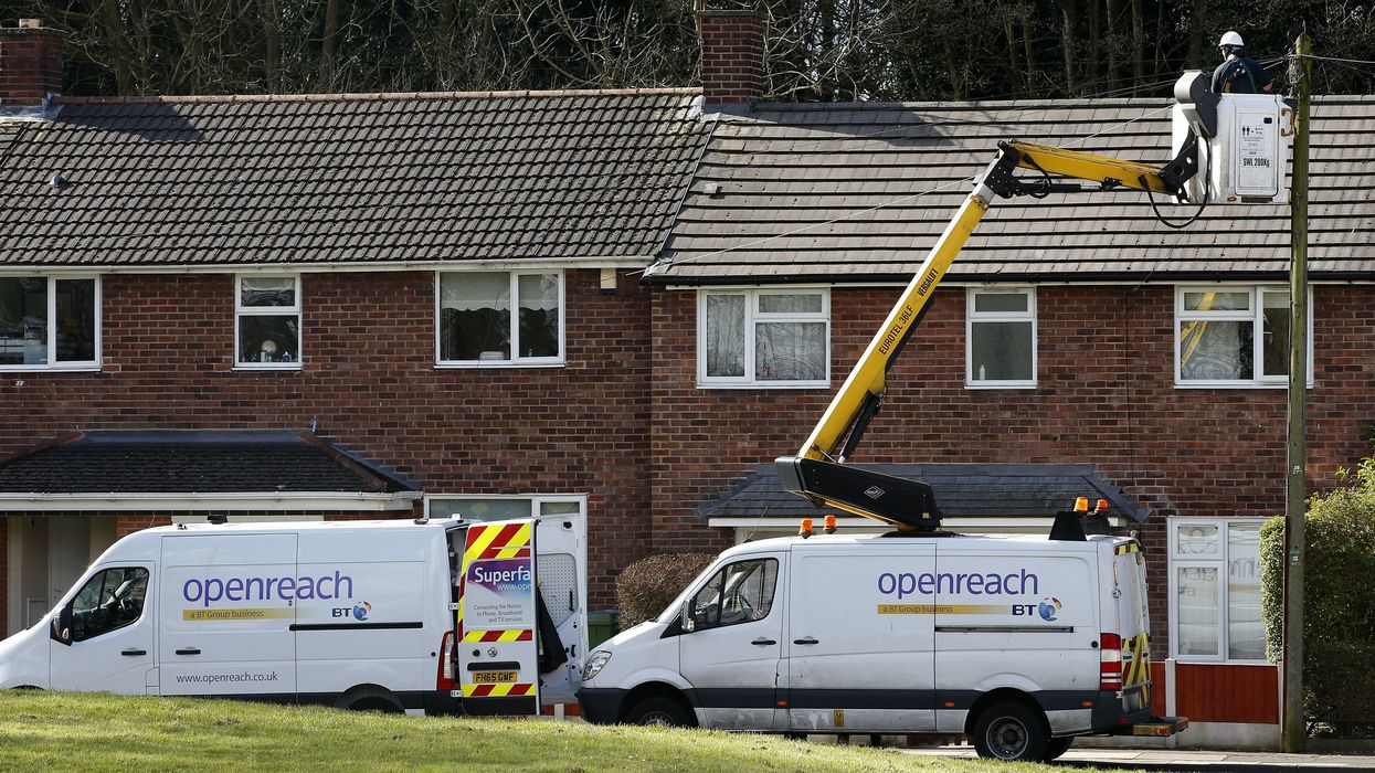 two openreach vans are pictured outside of terrace homes with an engineer repairing a cable