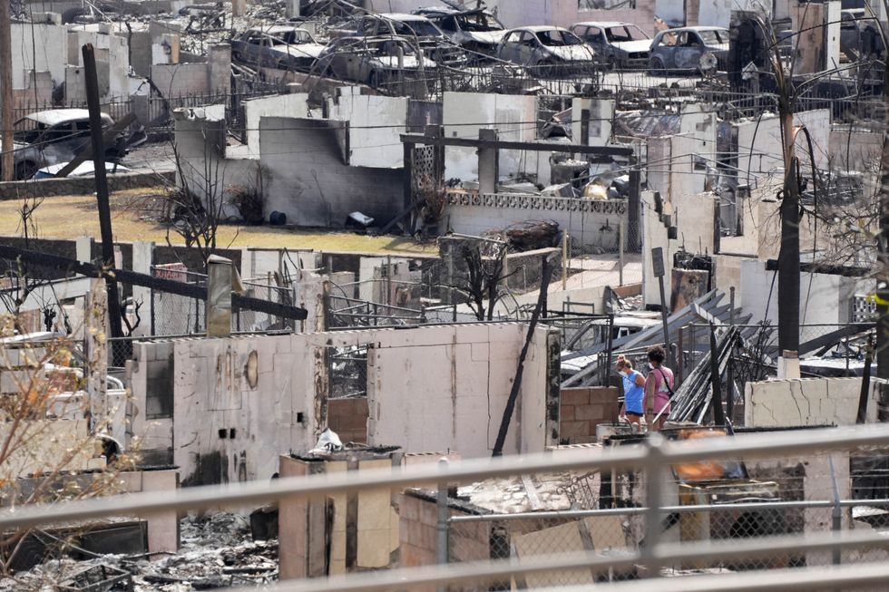 Two people examine a burned house after an inferno destroyed much of the historic Maui resort town of Lahaina