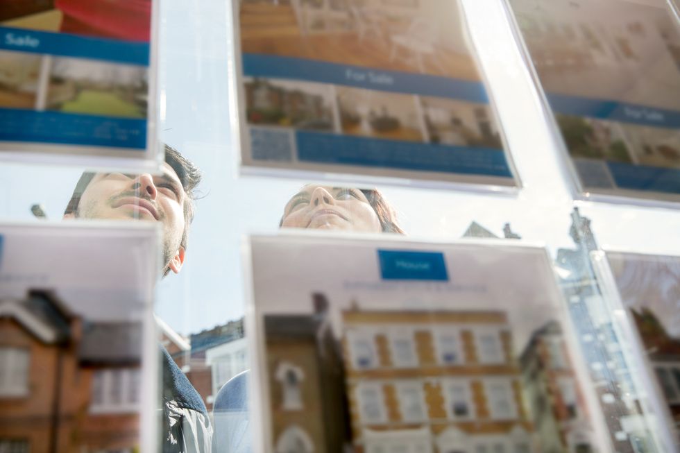 Two people looking at the properties on sale in the front of an agency