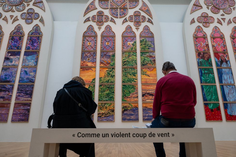 Two people sit on a bench in front of Claire Tabouret's window to be installed in Notre Dame