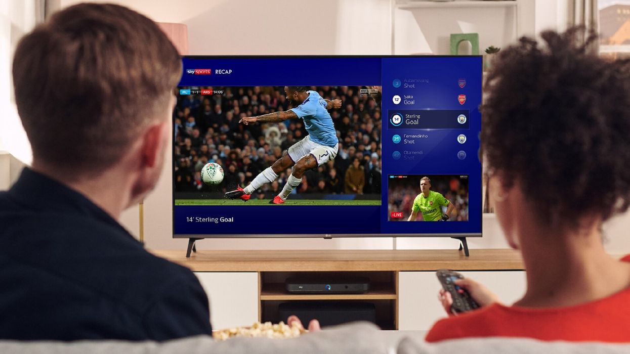 two people sit watching sky sports on the sofa