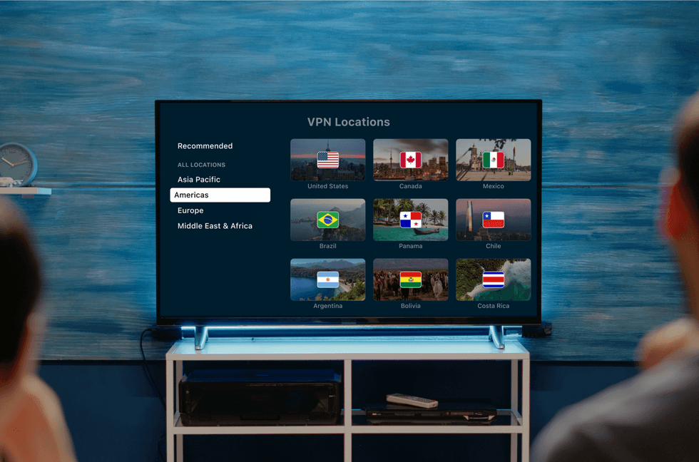 two people sitting in front of a smart tv with a list of VPN server locations from ExpressVPN on-screen