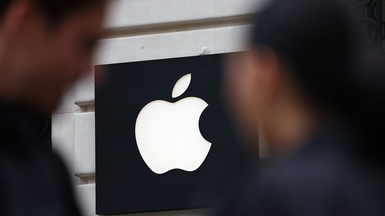 two people walking outside of the apple store in paris with the apple logo shown