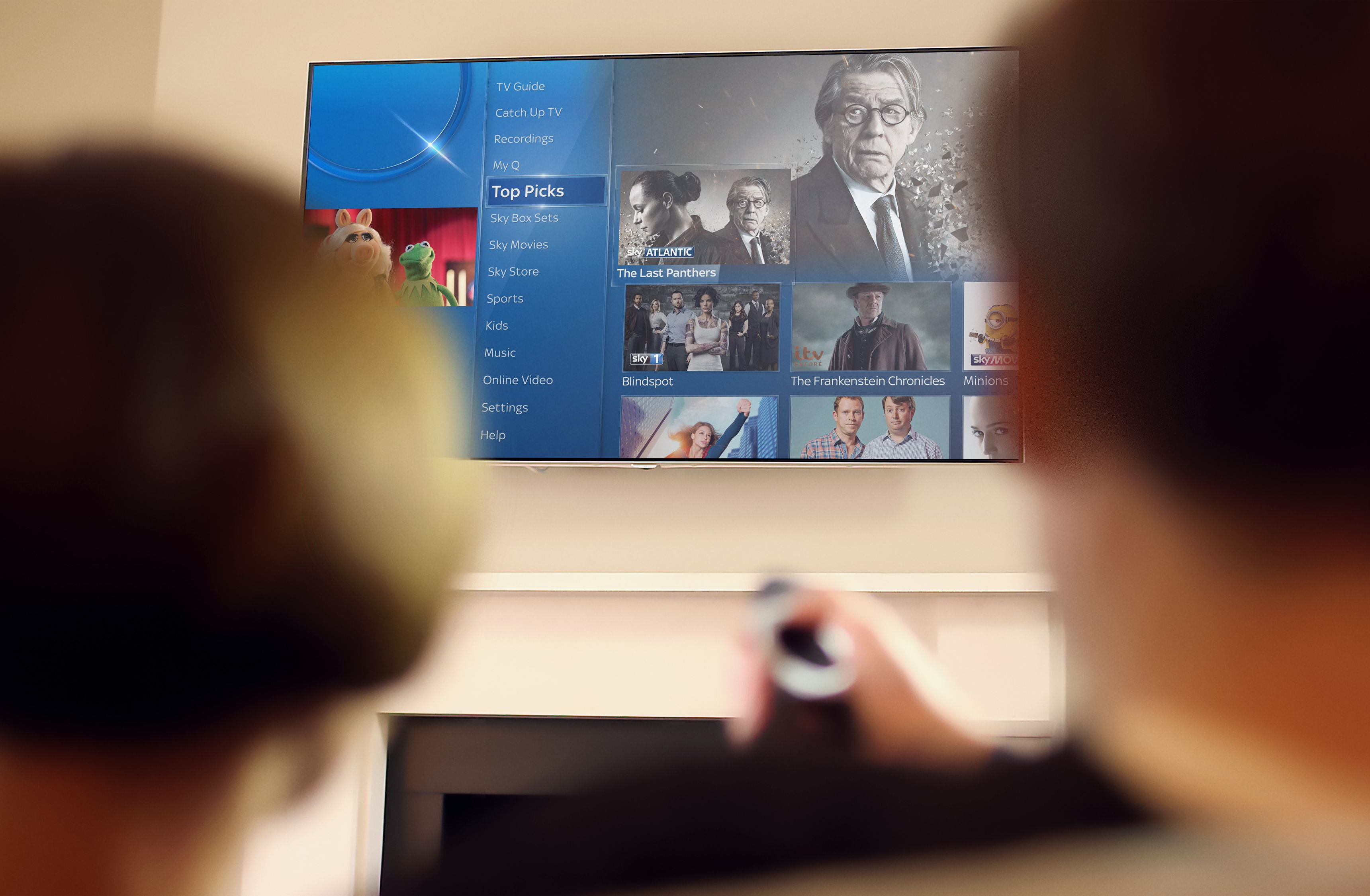 two people watching television with a Sky Q remote