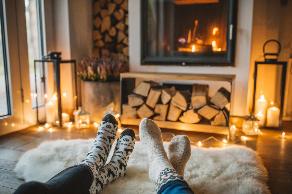 Two people with feet up on a fur rug in front of a fire