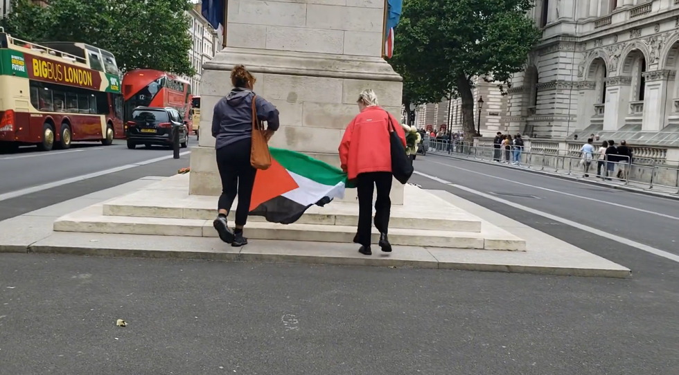 Two protesters place a flag on the steps of the Cenotaph