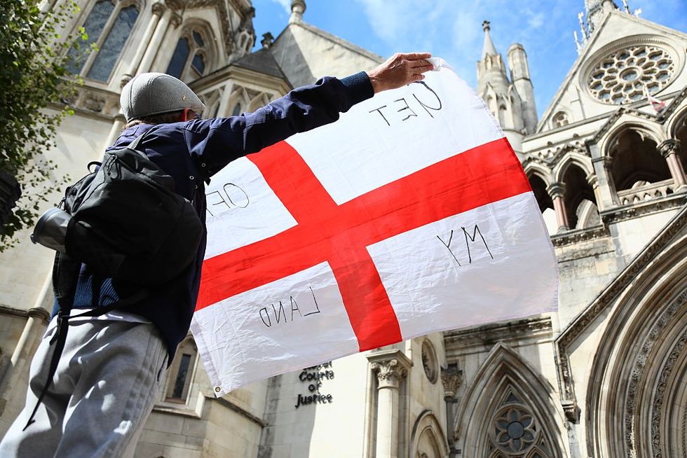 \u200b A protester holds the flag of St George outside the Court of Appeal ruling on housing migrants