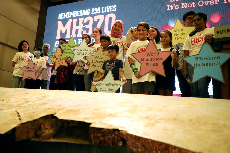\u200b Family members of the victims pose for a group picture with a debris of the missing Malaysia Airlines flight MH370