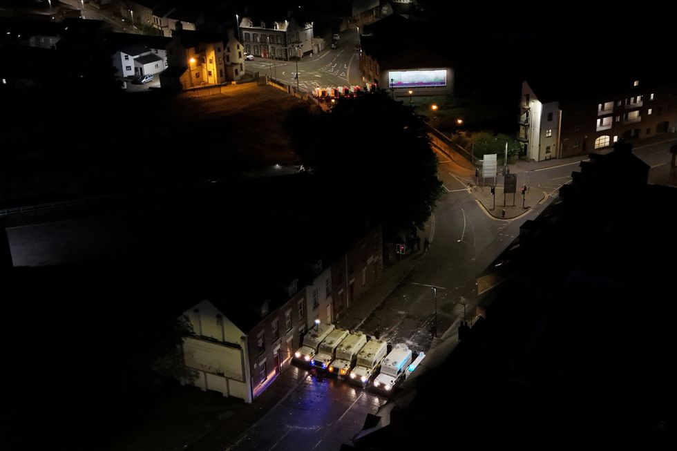 \u200bA drone view shows riot police vehicles lined up to block a road
