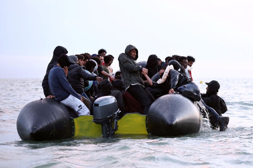 \u200bA group of migrants get on an inflatable dinghy in an attempt to cross the English Channel