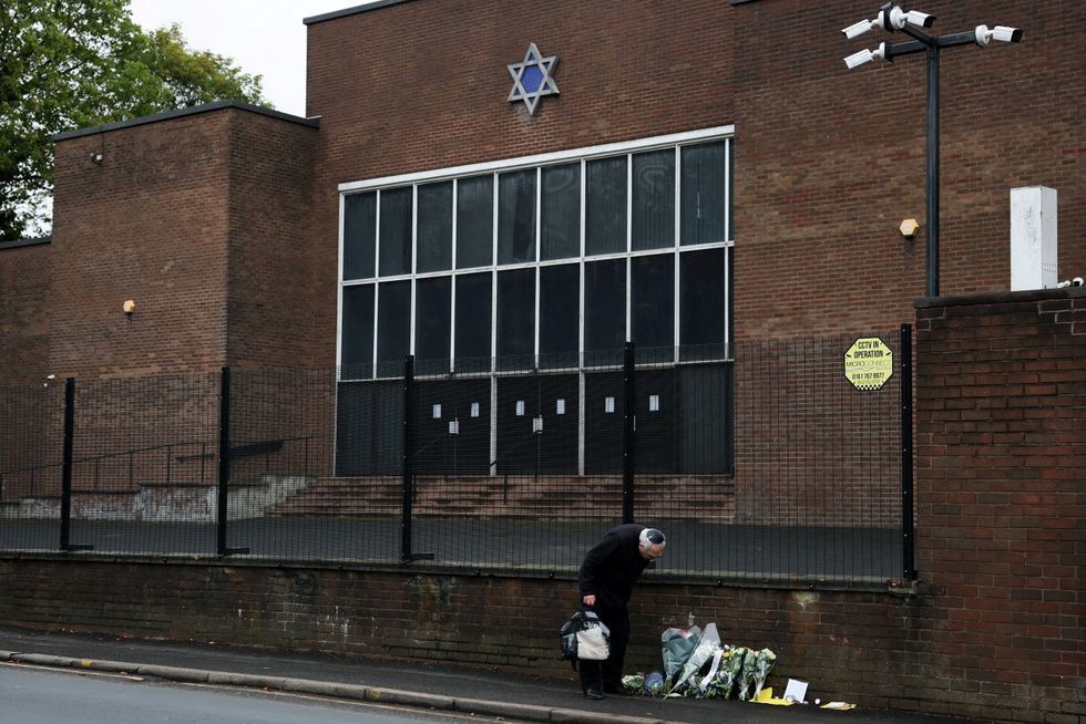 \u200bA man looks at floral tributes outside the Manchester synagogue,