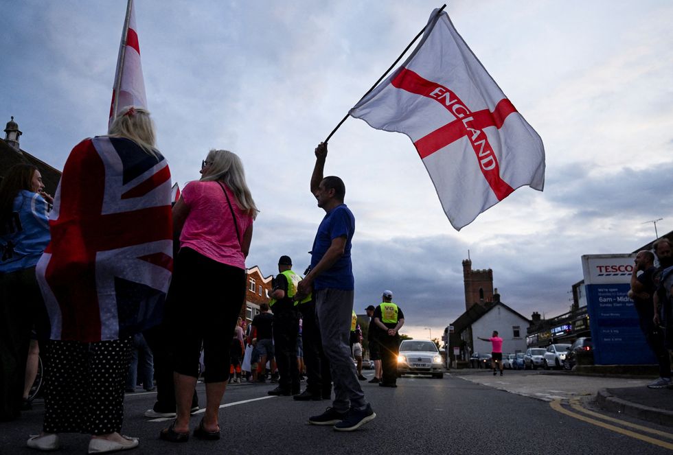 \u200bA man waves a flag with 'England' written on it, as protesters gather during an anti-immigration demonstration
