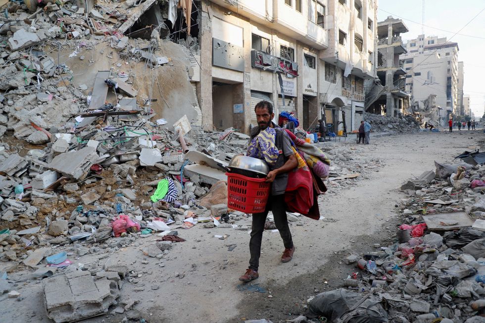 \u200bA Palestinian man carries his belongings during an Israeli military operation,