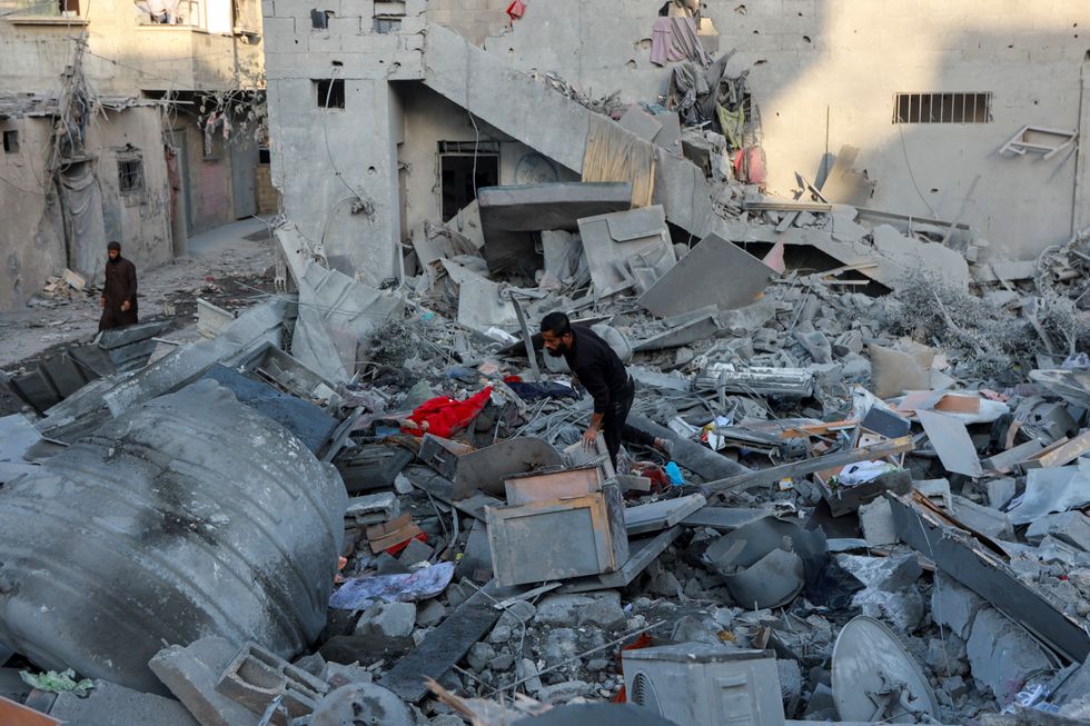 \u200bA Palestinian man walks through the rubble at the site of an Israeli strike on a house in Gaza