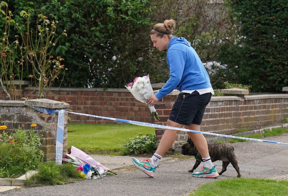 \u200bA person leaves flowers outside a property on Hammond Road in Woking, Surrey,