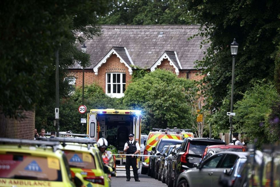 \u200bA police officer stands guard next to an ambulance behind a cordon following a car collision at the private Study Prep girls' school in Wimbledon