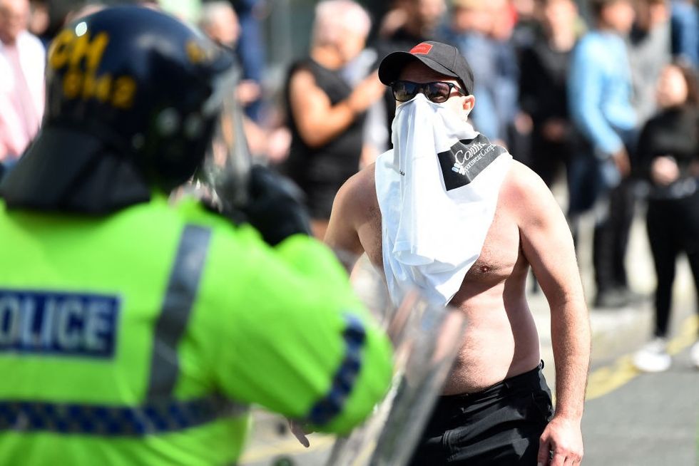\u200bA protester stands opposite a police officer in Liverpool
