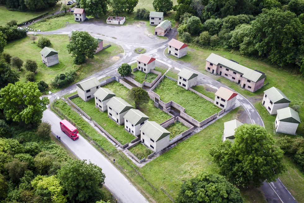 \u200bA Routemaster bus passes bulidings and former houses in the desserted village of Imber
