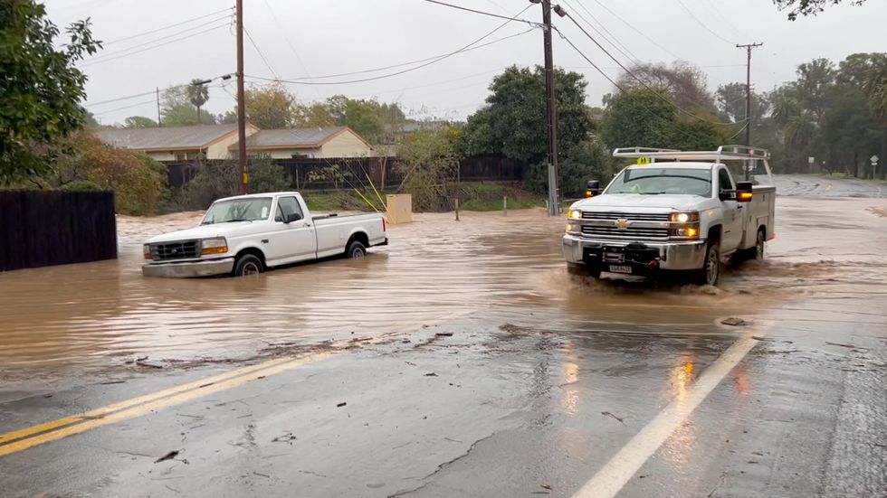 \u200bA vehicle drives on a flooded street in Santa Barbara, California