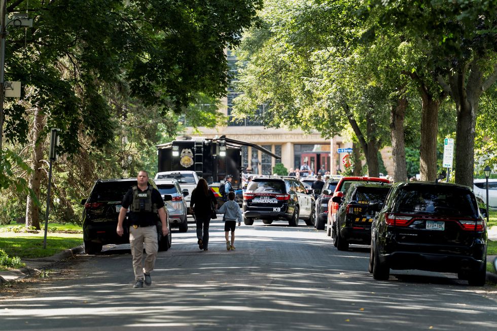 \u200bA woman and child holds hands, as they walk toward the site of the shooting at Annunciation Church