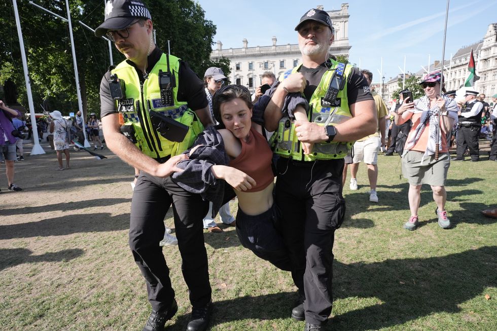 \u200bA woman is detained by police officers as supporters of Palestine Action