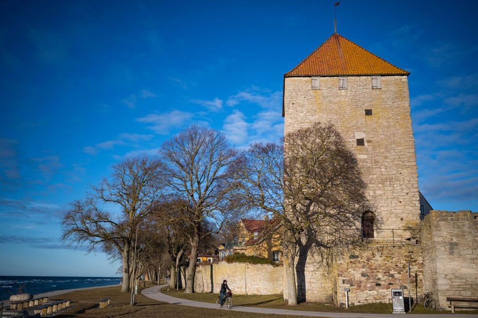 \u200bA woman rides her bike outside Visby City Wall,