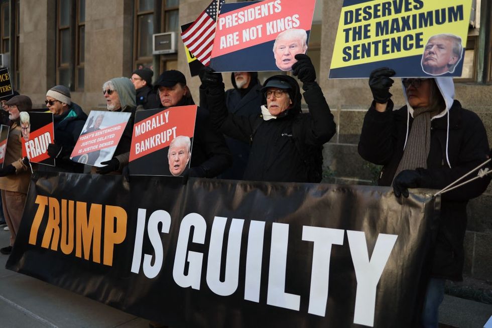 \u200bAnti-Trump supporters hold signs outside the Manhattan Criminal Court in New York