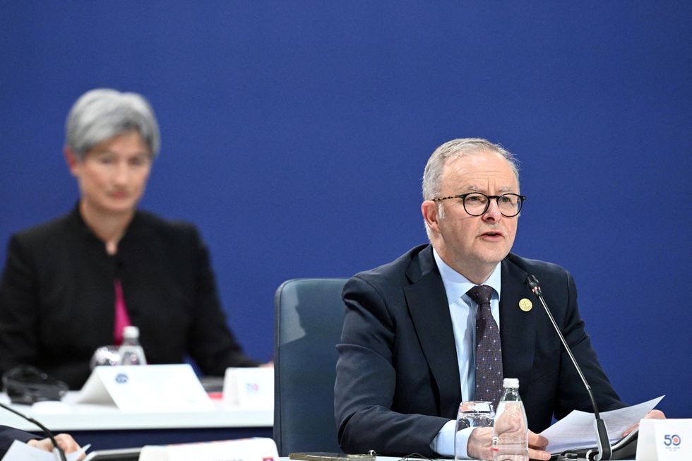 \u200bAustralian Prime Minister Anthony Albanese sitting with a microphone in a convention centre