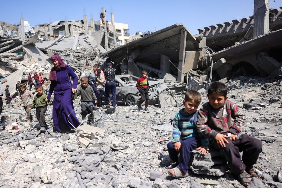 \u200bChildren look on as people walk amid the rubble of a building destroyed in an overnight Israeli strike in Jabalia,