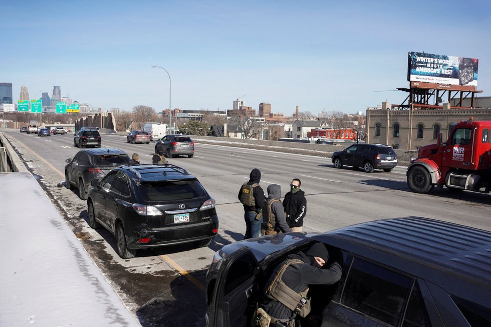 \u200bFederal immigration agents stand at Interstate 35W, while conducting immigration enforcement tasks in Minneapolis