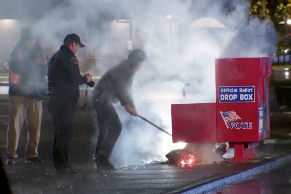 \u200bFirst responders pull out the burning contents of a ballot box
