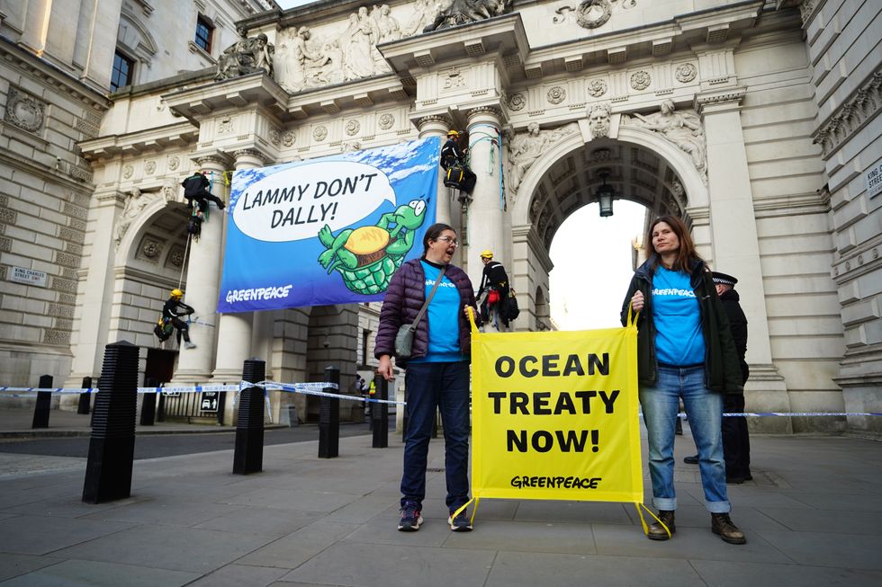 \u200bFour Greenpeace activists unfurl a banner saying 'Lammy don't dally'