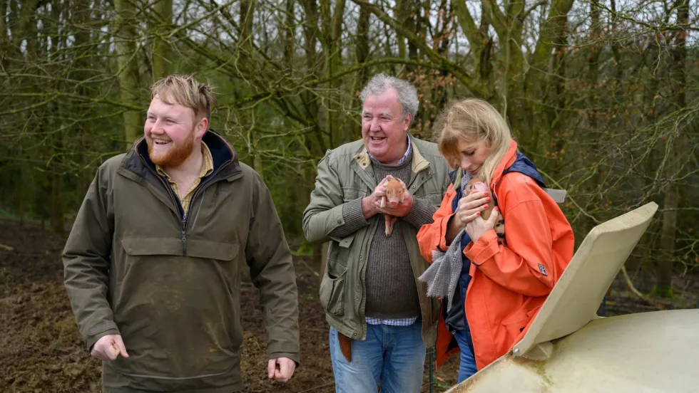 \u200bJeremy Clarkson, Lisa Hogan, and Kaleb Cooper pictured holding piglets in clarksons farm 3 series