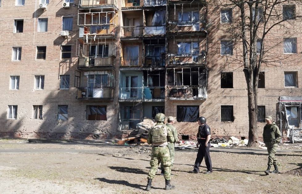 \u200bLocal volunteers walk past a building damaged by Ukrainian strikes in Kursk on August 16, 2024,