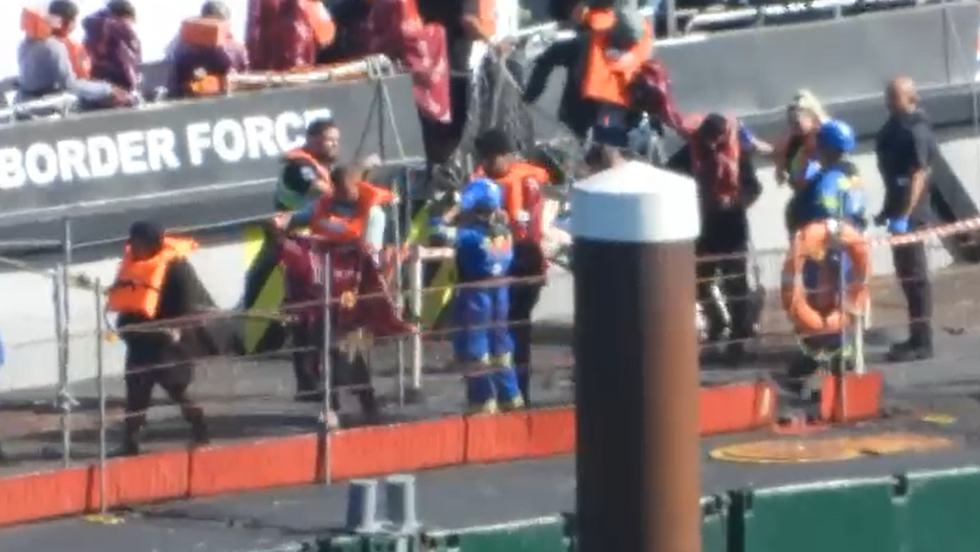 \u200bMigrants are seen wrapping themselves in blankets after arriving in Dover