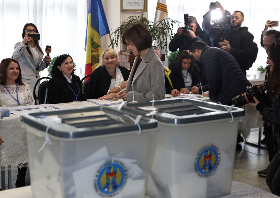 \u200bMoldova's incumbent President and presidential candidate Maia Sandu stands in front of members of a local electoral commission at a polling station