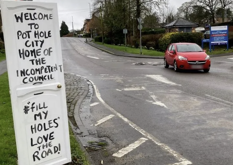 \u200bOne of the signs on the road welcoming people to "Pot Hole City"