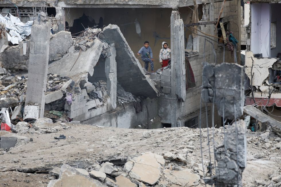 \u200bPalestinian children stand at the site of Thursday's Israeli strike on a house,